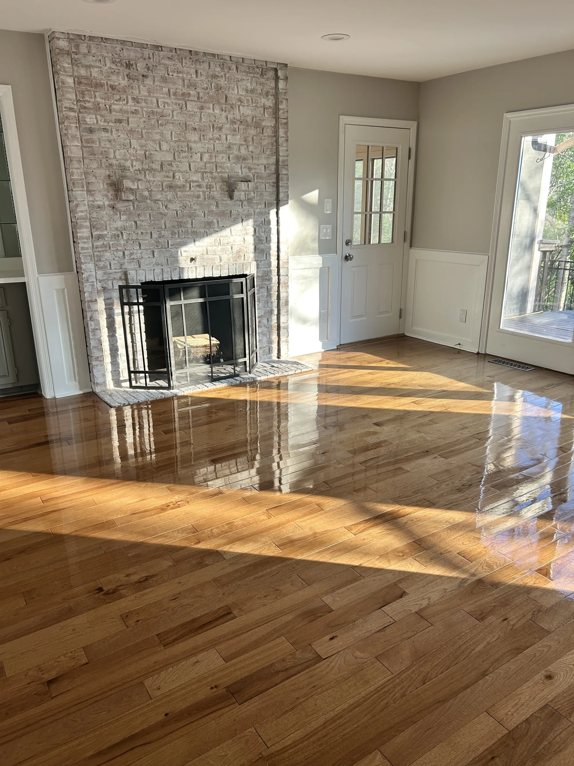 Freshly finished living room with brick fireplace and gleaming hardwood floors after a post-construction clean in Cincinnati